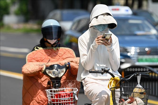 Người dân mặc áo chống nắng trên đường phố tại Thượng Hải, Trung Quốc, ngày 29/5/2023. Ảnh: AFP/TTXVN