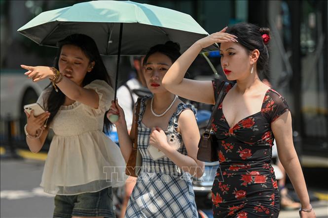 Người dân di chuyển trên đường phố dưới trời nắng nóng tại Thượng Hải, Trung Quốc, ngày 29/5/2023. Ảnh: AFP/TTXVN