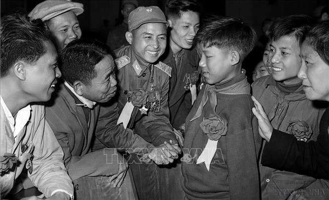 Các đại biểu tại Đại hội Anh hùng, Chiến sĩ thi đua toàn quốc lần thứ IV (1966) thăm hỏi em Hoa Xuân Tứ, học sinh lớp 6 (Nghệ An), bị cụt cả hai tay vẫn nỗ lực học tập, trở thành “Cháu ngoan Bác Hồ” và kiện tướng về thể dục. Ảnh: TTXVN
