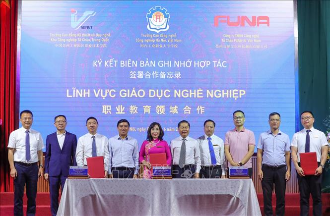 Giám đốc Công ty TNHH Công nghệ Tô Châu FUNA-AI Việt Nam Lu Jun và Hiệu trưởng trường CĐ Công nghiệp Hà Nội Phạm Thị Hường cùng Hiệu trưởng trường CĐ Kỹ thuật và Dạy nghề, khu Công nghiệp Tô Châu, Trung Quốc Wang Yinhai ký kết thỏa thuận hợp tác. Ảnh: Hoàng Hiếu - TTXVN