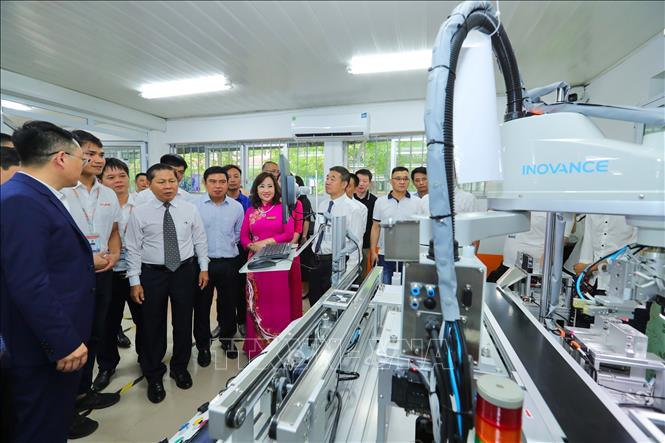 Thứ trưởng Bộ LĐ, TB&XH Lê Tấn Dũng và các đại biểu tham quan Trung tâm đào tạo sản xuất thông minh HNIVC-FUNA. Ảnh: Hoàng Hiếu - TTXVN