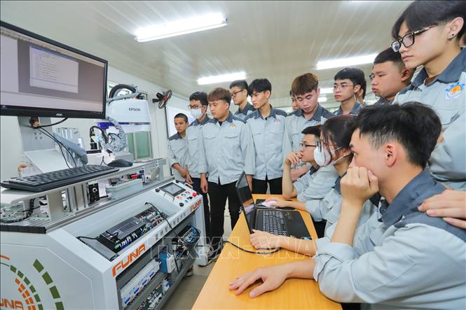 Sinh viên Cơ điện tử thực hành lập trìnhđiều khiển cánh tay robot tại Trung tâm đào tạo sản xuất thông minh HNIVC-FUNA. Ảnh: Hoàng Hiếu - TTXVN
