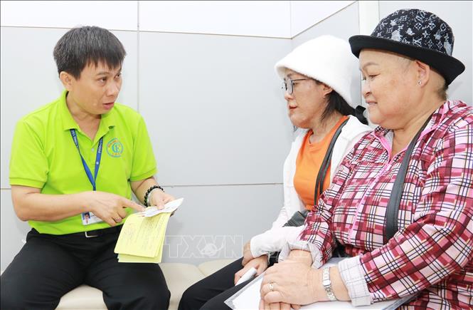 Trong ảnh: Thạc sĩ Lê Minh Hiển xem xét hồ sơ, giấy tờ để tìm cách trợ giúp cho bệnh nhân mắc bệnh hiểm nghèo. Ảnh: Đinh Hằng – TTXVN