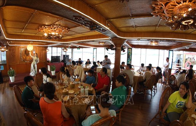 Trong ảnh: Du khách thưởng thức chương trình ẩm thực và ca nhạc trên Tàu Rồng Sông Hàn trước giờ xem pháo hoa. Ảnh: Trần Lê Lâm – TTXVN 