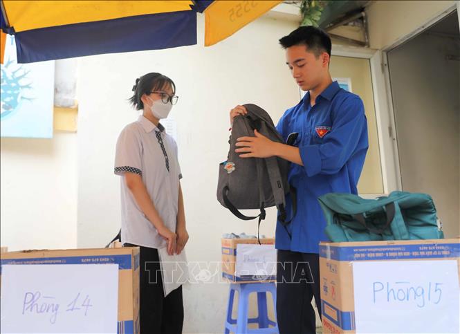 Tình nguyện viên hỗ trợ thí sinh gửi đồ cá nhân và dặn các em nhớ bỏ lại điện thoại để không vi phạm quy chế. Ảnh: Thanh Tùng - TTXVN 