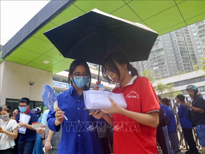 Thanh niên tình nguyện che ô cho thí sinh tại điểm thi trường THCS Trần Duy Hưng (quận Cầu Giấy). Ảnh: Tuấn Đức - TTXVN