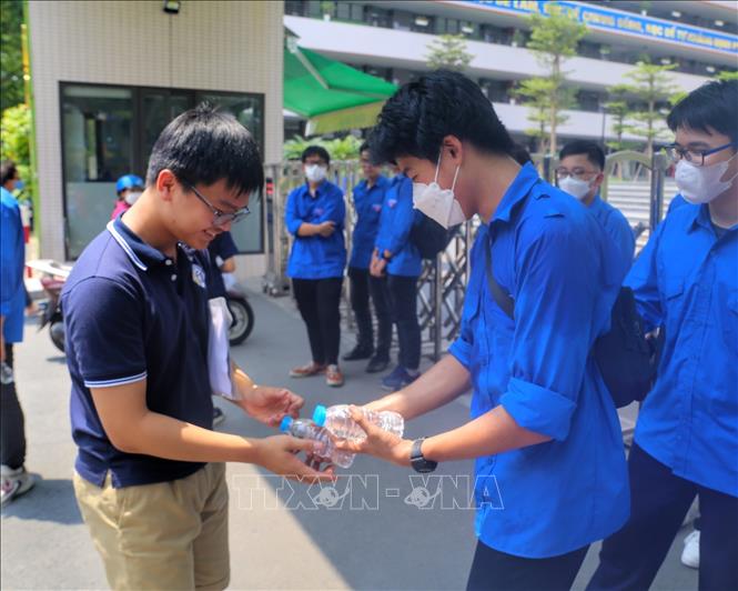 Thanh niên tình nguyện phát nước cho thí sinh tại điểm thi trường THCS Trần Duy Hưng (quận Cầu Giấy). Ảnh: Tuấn Đức - TTXVN
