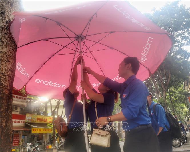 Lực lượng thanh niên tình nguyện dựng ô che nắng tại điểm thi trường THCS Ngô Sĩ Liên (quận Hoàn Kiếm). Ảnh: Tuấn Đức - TTXVN
