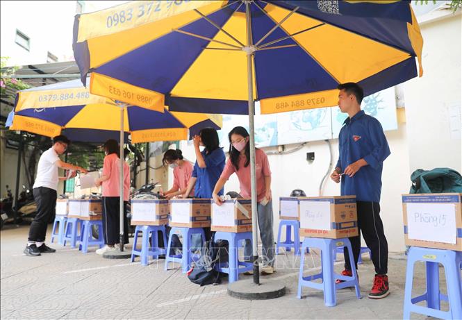 Tình nguyện viên có mặt từ sớm ở các điểm thi, hỗ trợ thí sinh gửi đồ cá nhân và không quên dặn các em nhớ bỏ lại điện thoại để không vi phạm quy chế. Ảnh: Thanh Tùng - TTXVN 