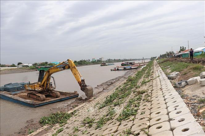 Máy thi công đặt đá để hoàn thành gia đoạn gia cố bờ kè. Ảnh: Hữu Chí - TTXVN