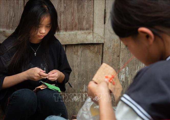 Trong ảnh: Các em gái dân tộc Mông học thêu đắp vải màu. Ảnh: Nam Thái - TTXVN