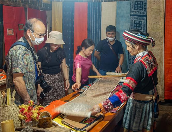 Trong ảnh: Khách du lịch tham quan, mua sắm các sản phẩm được dệt từ lanh. Ảnh: Nam Thái - TTXVN
