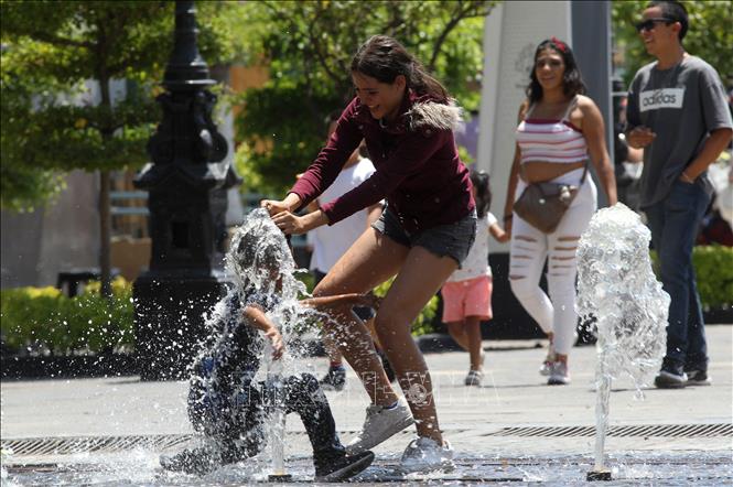 Trẻ em chơi đùa bên vòi phun nước để tránh nóng tại Guadalajara, bang Jalisco, Mexico, ngày 12/6/2023. Ảnh: AFP/TTXVN