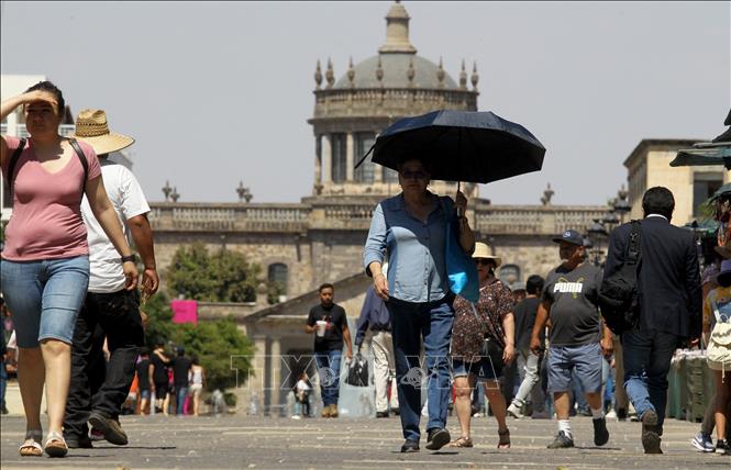 Người dân di chuyển trên đường phố dưới trời nắng nóng tại Guadalajara, bang Jalisco, Mexico, ngày 12/6/2023. Ảnh: AFP/TTXVN