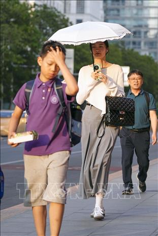 Người dân di chuyển trên đường phố thủ đô Bắc Kinh, Trung Quốc khi nhiệt độ lên tới 39 độ C, ngày 16/6/2023. Ảnh: Kyodo/TTXVN