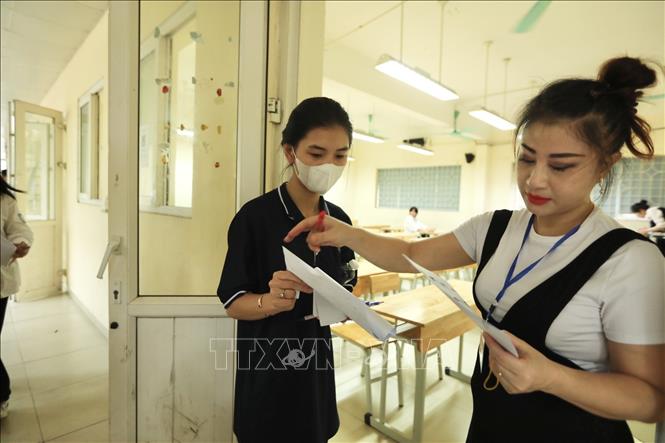 Giám thị gọi thí sinh vào phòng thi tại điểm thi trường THPT Nguyễn Gia Thiều (Hà Nội). Ảnh: Minh Quyết - TTXVN