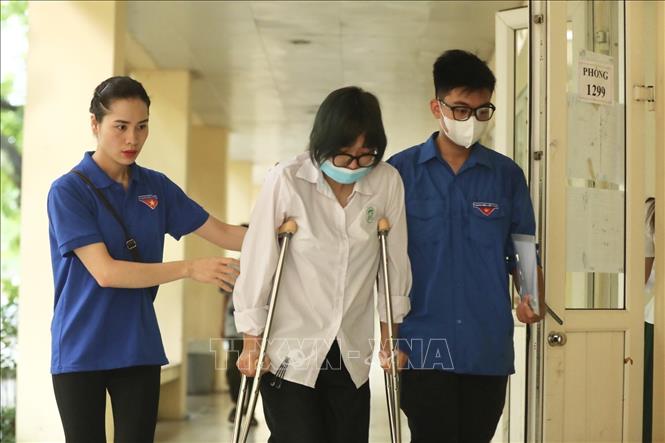 Tình nguyện viên hỗ trợ thí sinh bị đau chân đến điểm thi trường THPT Nguyễn Gia Thiều (Hà Nội). Ảnh: Minh Quyết - TTXVN