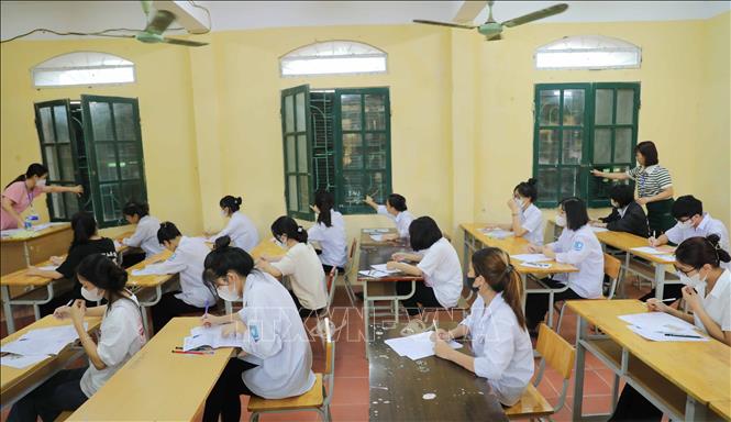 Giám thị phòng thi tại điểm thi Trường THPT Yên Mỹ (huyện Yên Mỹ, Hưng Yên) kiểm tra kỹ cửa sổ trước giờ làm bài thi môn Ngữ Văn. Ảnh: Thanh Tùng - TTXVN