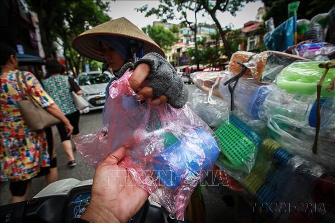 Một người bán đồ nhựa gia dụng đựng trong túi nylon cho khách trên phố Hà Nội. Ảnh: Trọng Đạt - TTXVN