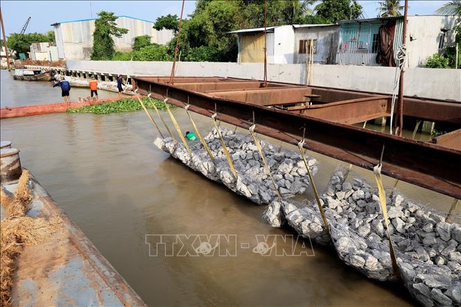 Trong ảnh: Hạ thủy giằng đá xuống bãi địa dưới lòng sông để làm kè chống sạt lở bờ sông Tiền. Ảnh: Hồng Đạt - TTXVN
