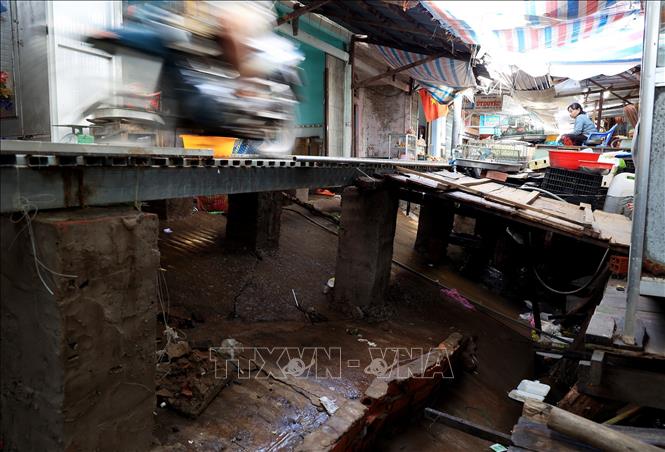 Trong ảnh: Cây cầu sắt tạm thay con đường bị sạt lở, sụt lún chạy trong chợ Tân Tiến, gặp trời mưa trơn trượt khiến nhiều xe máy, người dân đi lại bị té ngã. Ảnh: Hồng Đạt - TTXVN
