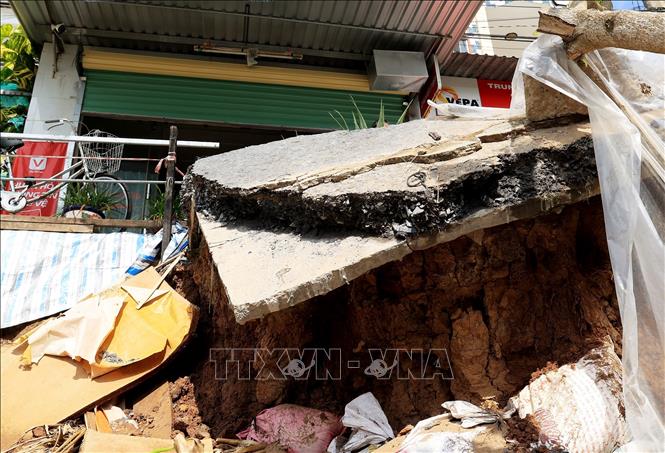 Trong ảnh: Một mảng bê tông, nhựa đường chỉ chờ rớt xuống sông do sạt lở. Ảnh: Hồng Đạt - TTXVN
