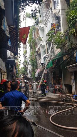 Lực lượng chức năng phải phá cửa để đưa vòi nước vào trong nhà dập lửa. Ảnh: Tuấn Anh - TTXVN
