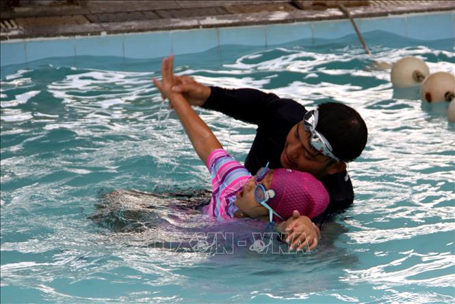 Các thầy, cô dạy học sinh kỹ năng bơi. Ảnh: Trịnh Bang Nhiệm - TTXVN
