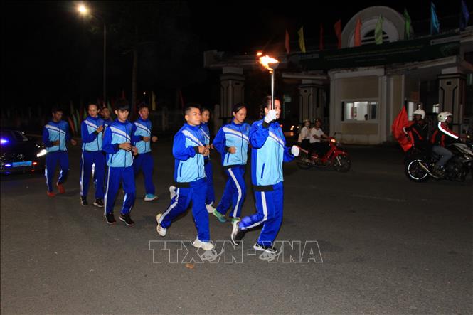 Vận động viên Huỳnh Thị Diệu Thảo cùng đoàn rước đuốc di chuyển từ khu di tích Chiến Thắng Chương Thiện về sân lễ. Ảnh: Nguyễn Hằng - TTXVN