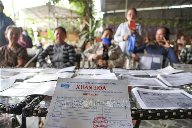 Người dân khốn đốn mang theo giấy biên nhận của tiệm vàng Xuân Hoa đi đòi nợ. Ảnh: Giang Phương - TTXVN