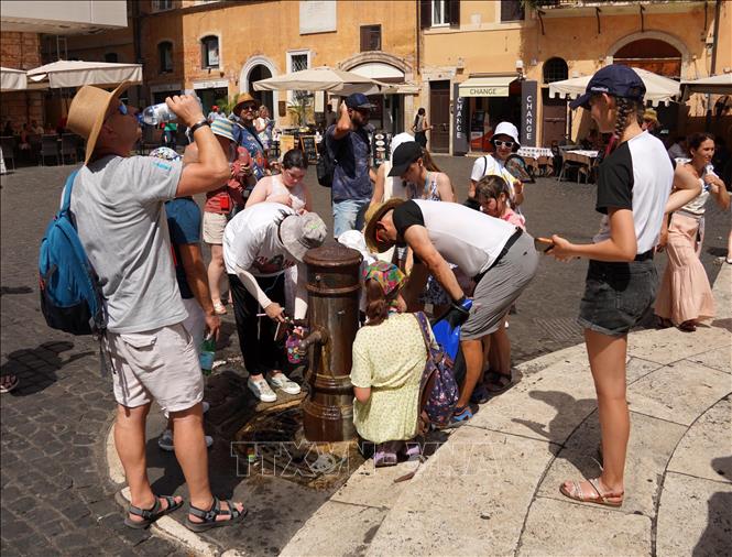 Người dân uống nước giải nhiệt khi nắng nóng bao trùm Rome, Italy, ngày 18/7/2023. Ảnh: THX/TTXVN