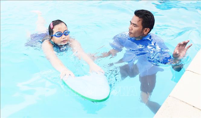 Các em nhỏ được huấn luyện viên dạy bơi tại Hồ bơi Trung tâm Huấn luyện và Thi đấu thể thao tỉnh Trà Vinh. Ảnh: Thanh Hòa-TTXVN 