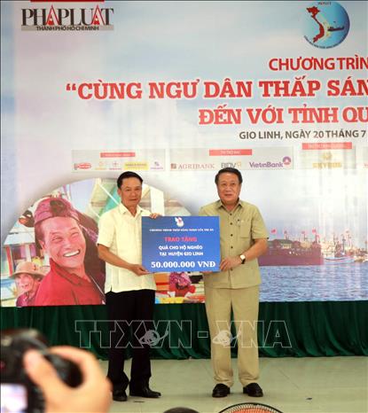 Ông Nguyễn Đức Lợi, Phó Chủ tịch Thường trực Hội Nhà báo Việt Nam trao bảng tượng trưng 50 phần quà cho bà con có hoàn cảnh khó khăn tại Quảng Trị. Ảnh: Nguyên Linh-TTXVN