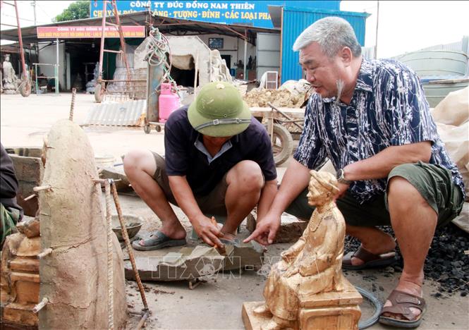 Cựu chiến binh Phan Trọng Điền (phải), Giám đốc Công ty TNHH MTV đúc đồng Nam Thiên (xã Xuân Ninh, huyện Xuân Trường) hướng dẫn công nhân làm việc. Ảnh: Nguyễn Lành - TTXVN 