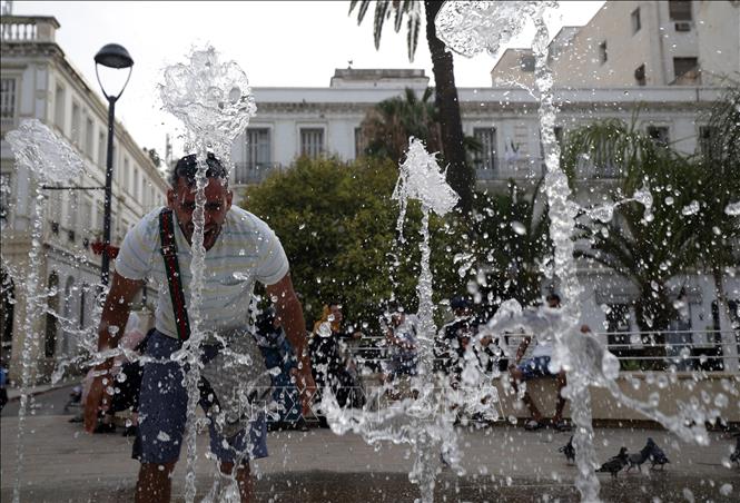 Người dân làm mát tại đài phun nước khi nhiệt độ tăng cao ở Algiers, Algeria, ngày 10/7/2023. Ảnh: THX/TTXVN