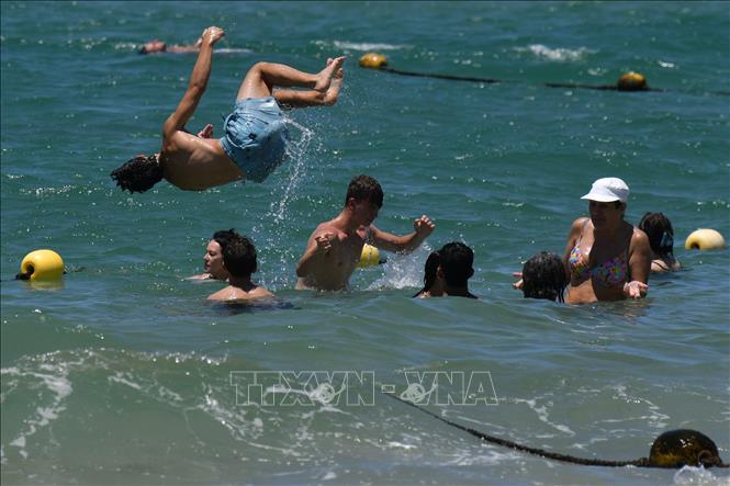 Người dân tắm biển nhằm giải nhiệt tại thành phố Tel Aviv, Israel, ngày 12/7/2023. Ảnh: THX/TTXVN