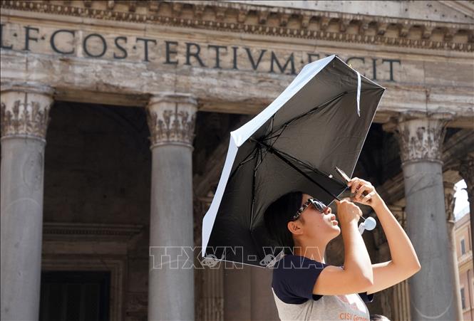 Du khách che ô khi di chuyển trong nắng gắt tại Rome, Italy ngày 18/7/2023. Ảnh: THX/TTXVN