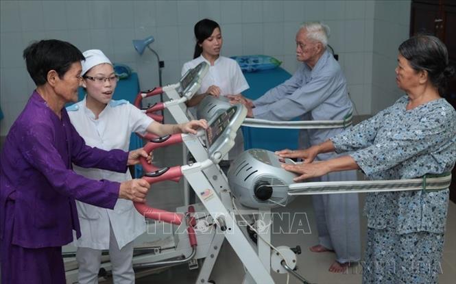 Hướng dẫn người có công tập phục hồi chức năng tại Trung tâm chăm sóc người có công với cách mạng tỉnh Bình Định. Ảnh: Anh Tuấn - TTXVN