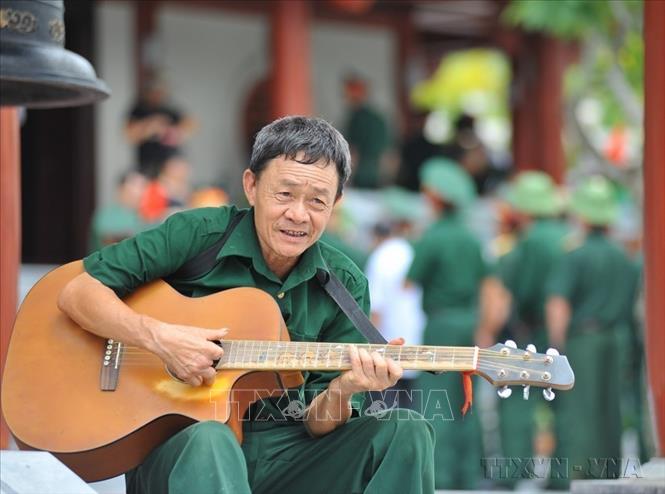 Cựu chiến binh mặt trận Vị Xuyên (Hà Giang) đàn hát cho đồng đội nghe tại Nghĩa trang liệt sĩ quốc gia Vị Xuyên (Hà Giang). Ảnh: Nam Thái - TTXVN  
