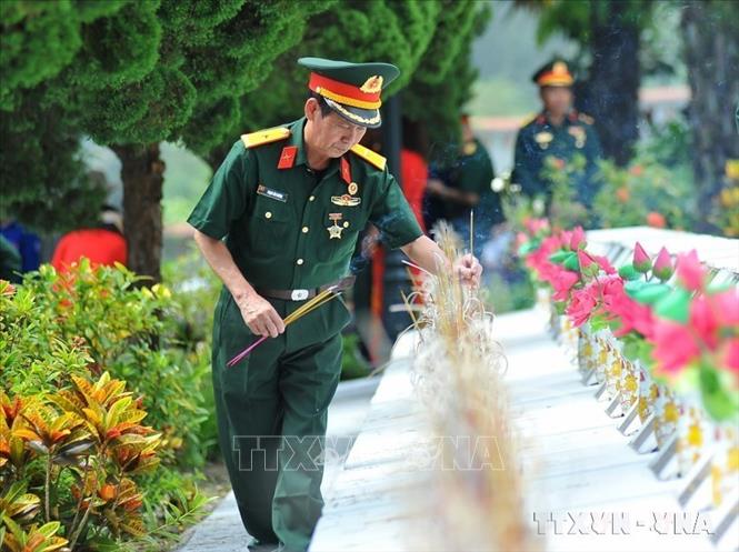 Các cựu chiến binh thắp hương tưởng nhớ các liệt sĩ tại Nghĩa trang liệt sĩ quốc gia Vị Xuyên (Hà GIang). Ảnh: Nam Thái - TTXVN