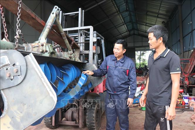 Anh Phùng Văn Nam (bên trái) giới thiệu sản phẩm máy cày phay lên luống đến với người dân. Ảnh: Thanh Thương- TTXVN