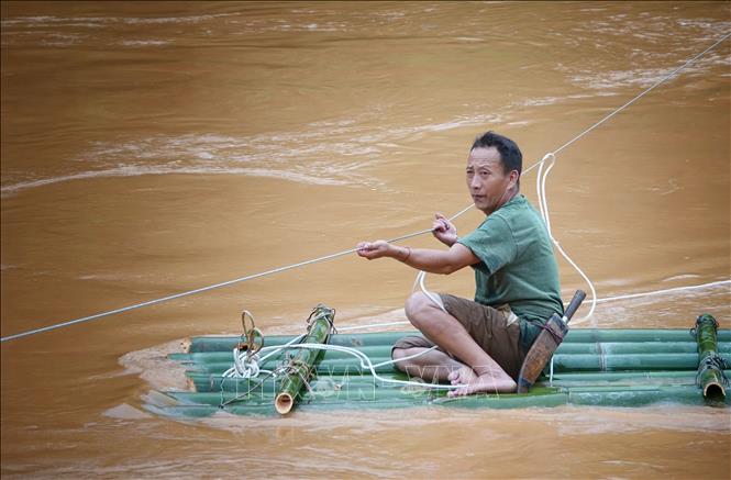 Nhờ có cáp treo mà lực lượng dân quân đã thuận lợi vào giúp đỡ các hộ bị ảnh hưởng do mưa lũ. Ảnh: Tuấn Anh-TTXVN
