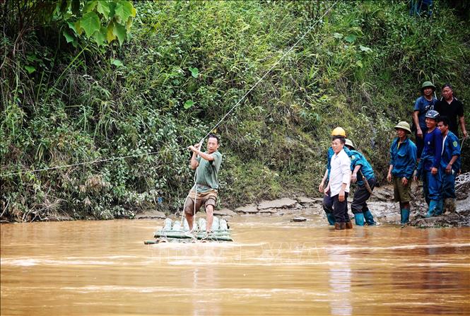 Nhờ có cáp treo mà lực lượng dân quân đã thuận lợi vào giúp đỡ các hộ bị ảnh hưởng do mưa lũ. Ảnh: Tuấn Anh-TTXVN

