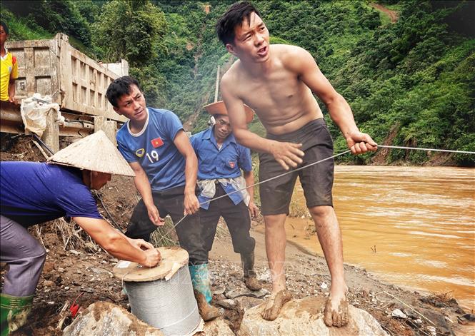 Nhờ có cáp treo mà lực lượng dân quân đã thuận lợi vào giúp đỡ các hộ bị ảnh hưởng do mưa lũ. Ảnh: Tuấn Anh-TTXVN

