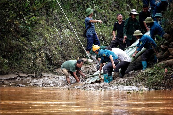 Nhờ có cáp treo mà lực lượng dân quân thuận lợi vào giúp đỡ các hộ bị ảnh hưởng do mưa lũ. Ảnh: Tuấn Anh-TTXVN

