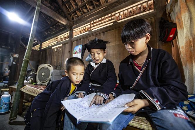 Trong ảnh: Ba người cháu được ông Lý Văn Hềnh truyền dạy chữ Dao mỗi ngày tại nhà. Ảnh: Trọng Đạt - TTXVN
