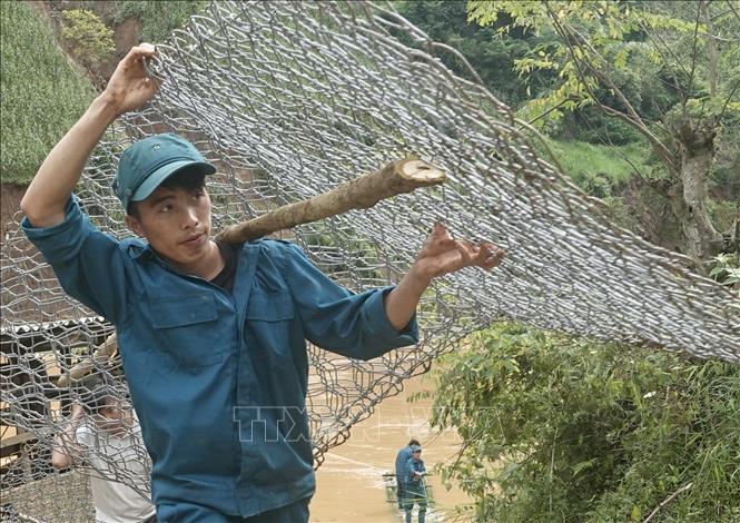 Lực lượng dân quân vận chuyển rọ đá đi khắc phục các tuyến đường bị hư hỏng tại bản Đề Sủa, xã Lao Chải Hồ. Ảnh: Tuấn Anh - TTXVN