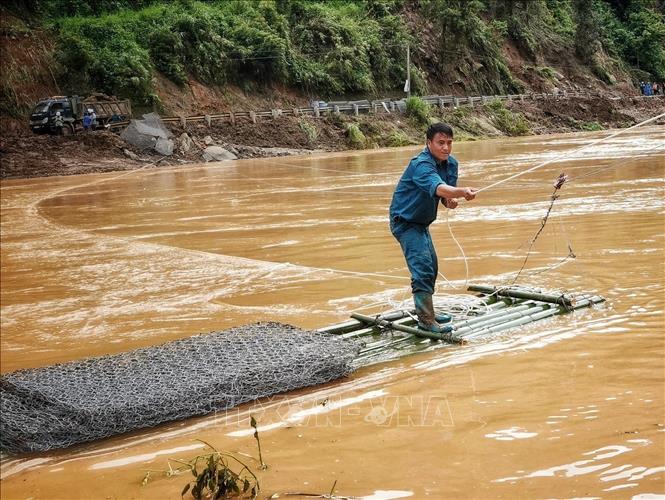 Dân quân dùng bè mảng vận chuyển rọ đá đi khắc phục các tuyến đường bị hư hỏng tại bản Đề Sủa xã Lao Chải Hồ. Ảnh: Tuấn Anh - TTXVN
