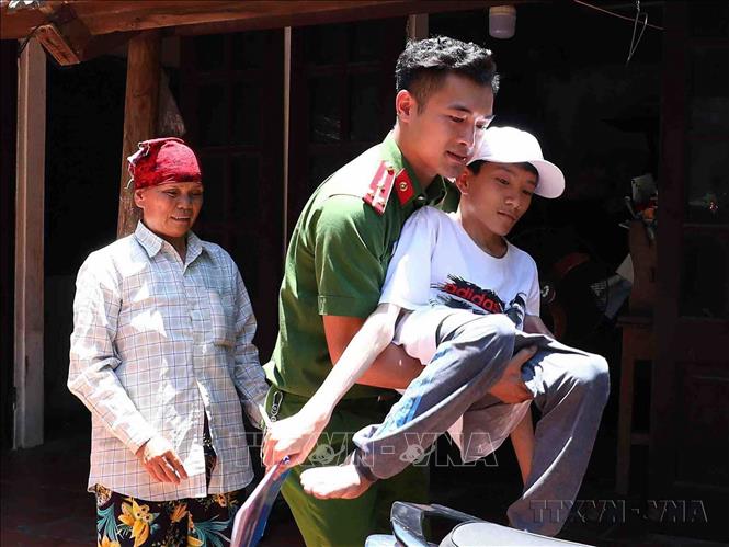 Đoàn viên, thanh niên Công an huyện Thạch Thất (Hà Nội) đến tận nhà đưa em Nguyễn Duy Phúc (học sinh trường THPT Thạch Thất) bị khuyết tật bẩm sinh, đi lại khó khăn, đến điểm thi trong Kỳ thi tốt nghiệp THPT 2023. Ảnh: Phạm Kiên - TTXVN