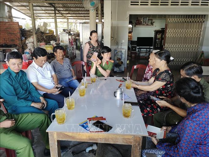 Trung tá Lê Thị Thùy Dung hỗ trợ người dân cài đặt đăng ký định danh mức hai trên điện thoại di động. Ảnh: Huỳnh Phúc Hậu - TTXVN